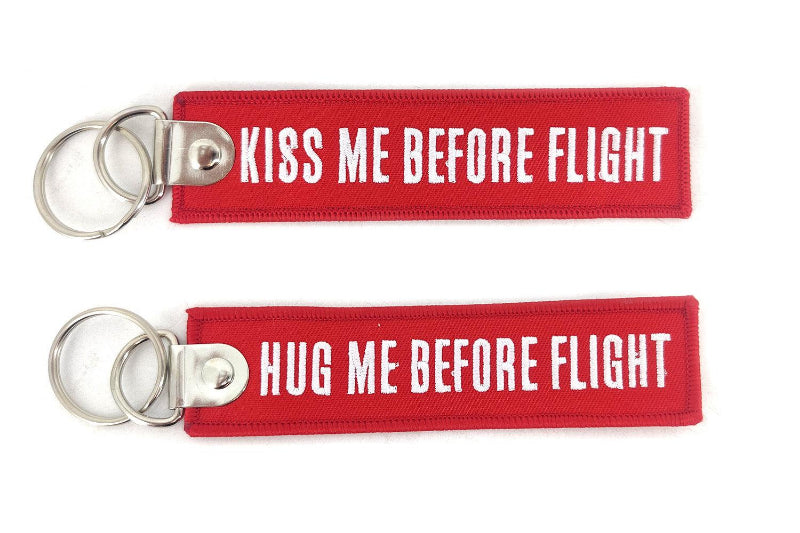 Porte-clés flamme rouge avec lettrage blanc "hug me before flight" au ercto et "kiss me before flight au verso"